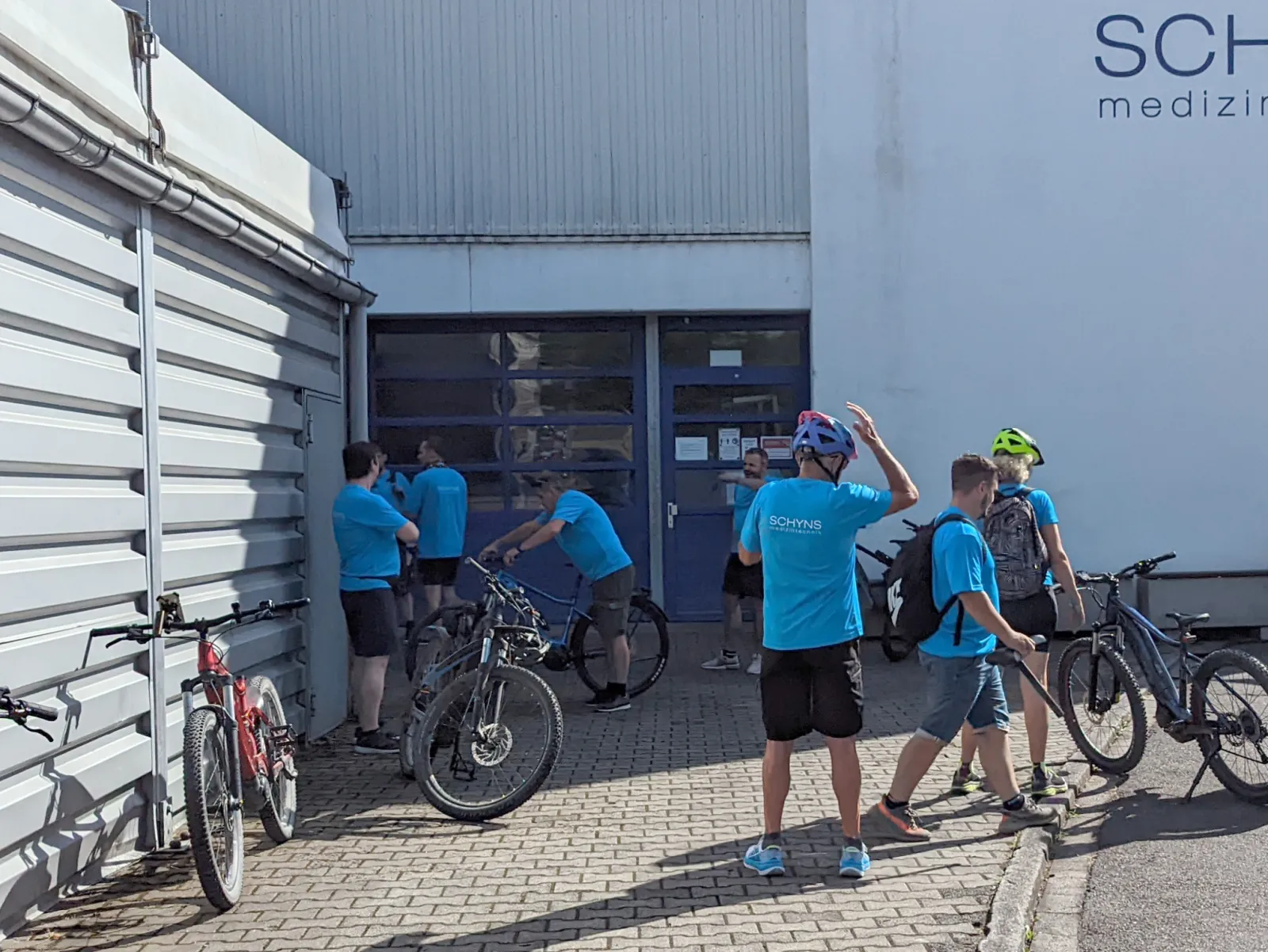 Employees with bicycles in Schyns jerseys in front of the company building