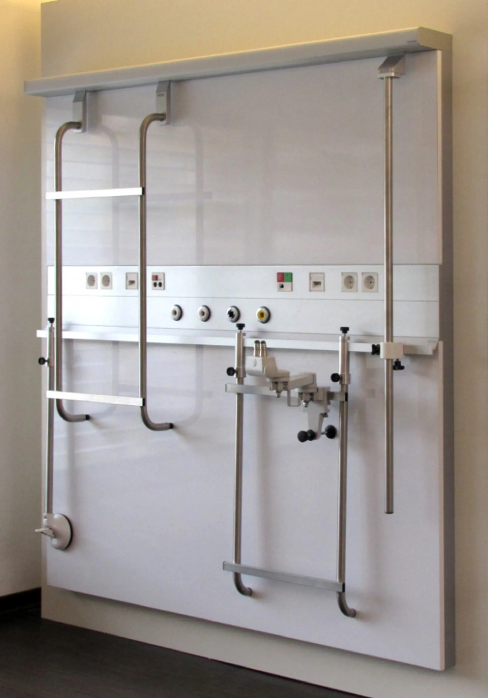 White medical wall console with several connections, levers and pipes in a room with light-coloured walls