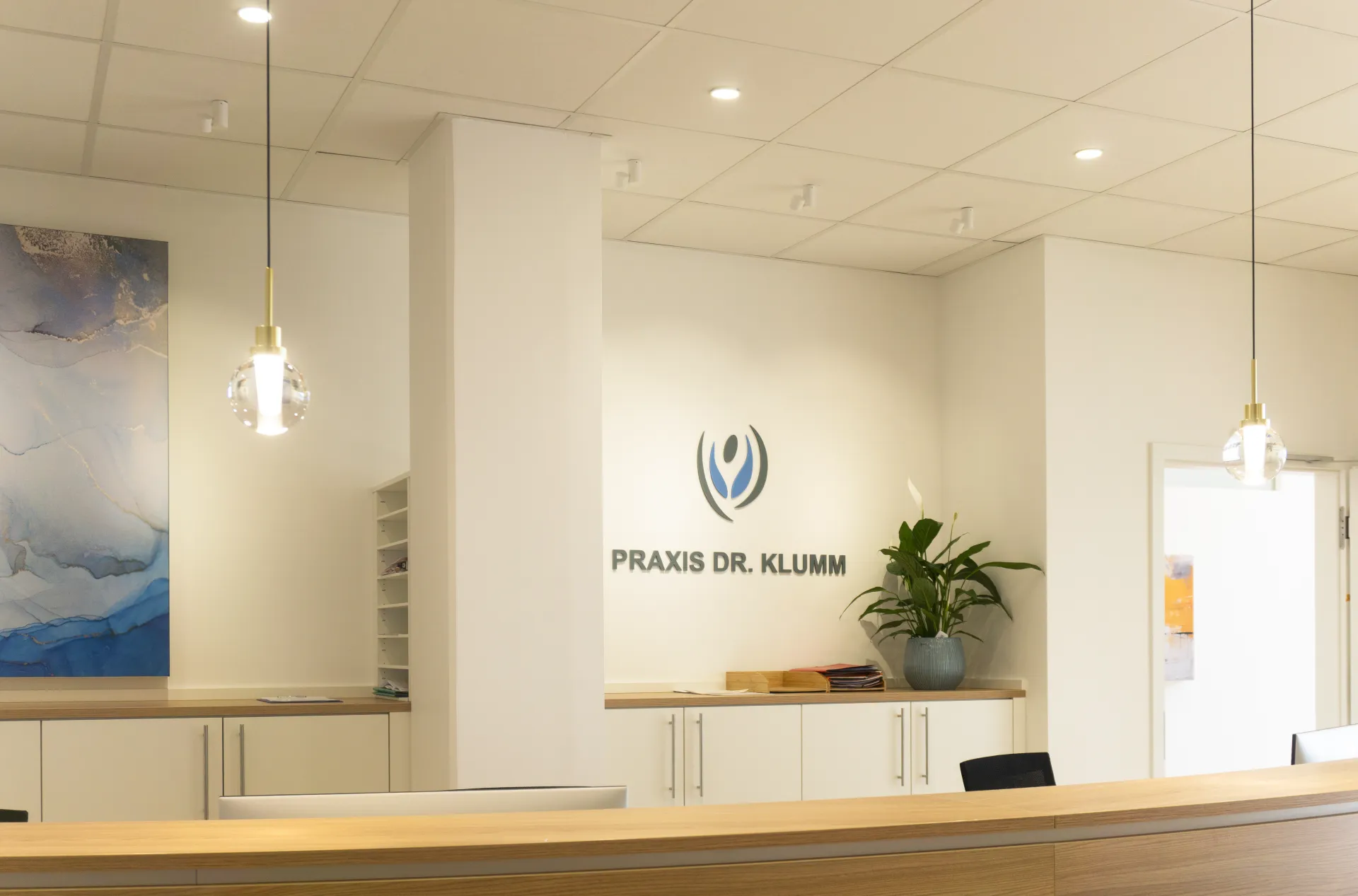 Entrance area of a practice, illuminated with the Alaska spherical pendant luminaire, Stram downlight and Buddy downlight.