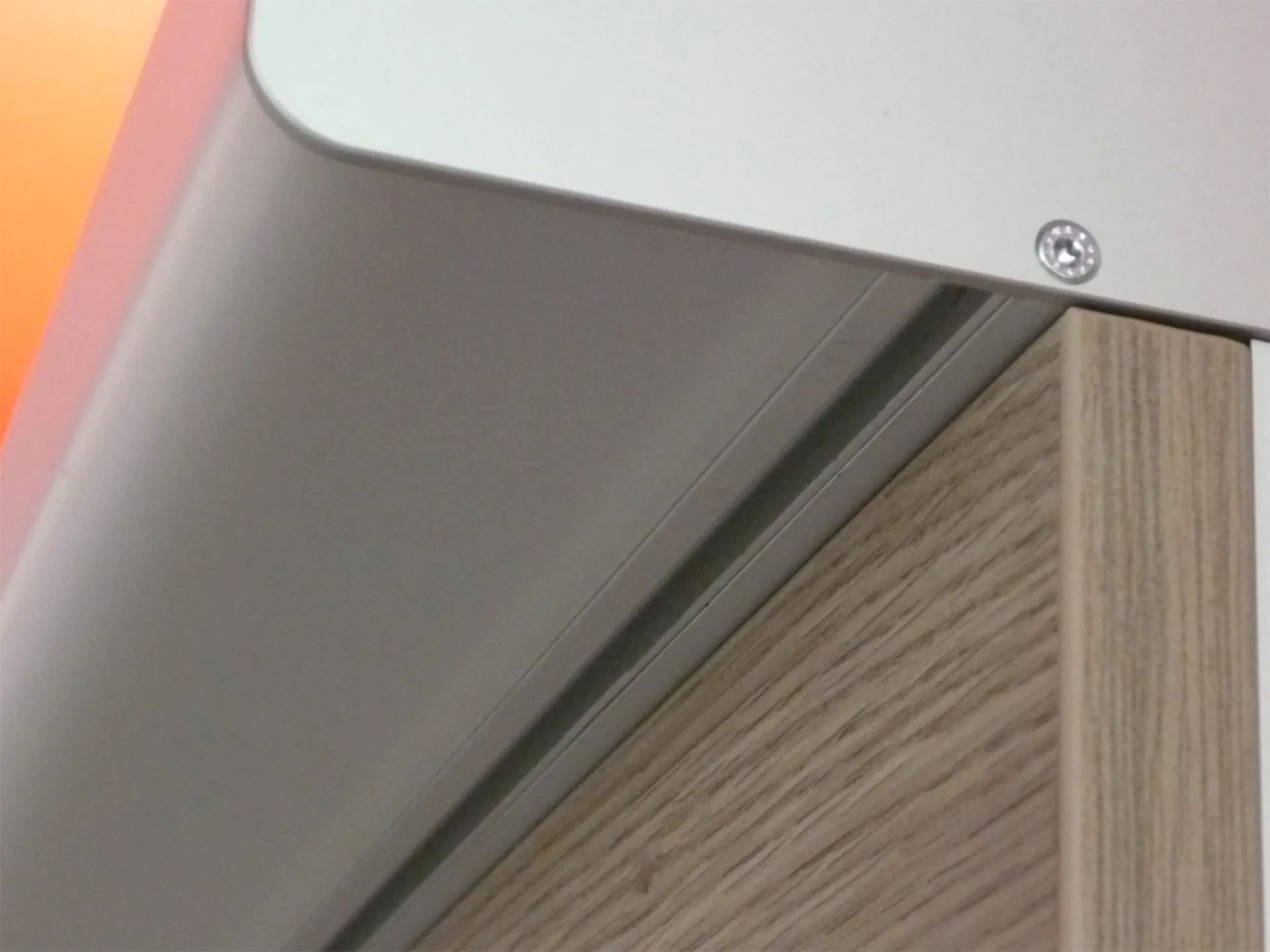 Close-up of a wooden panel with a metal profile and a screw in the corner
