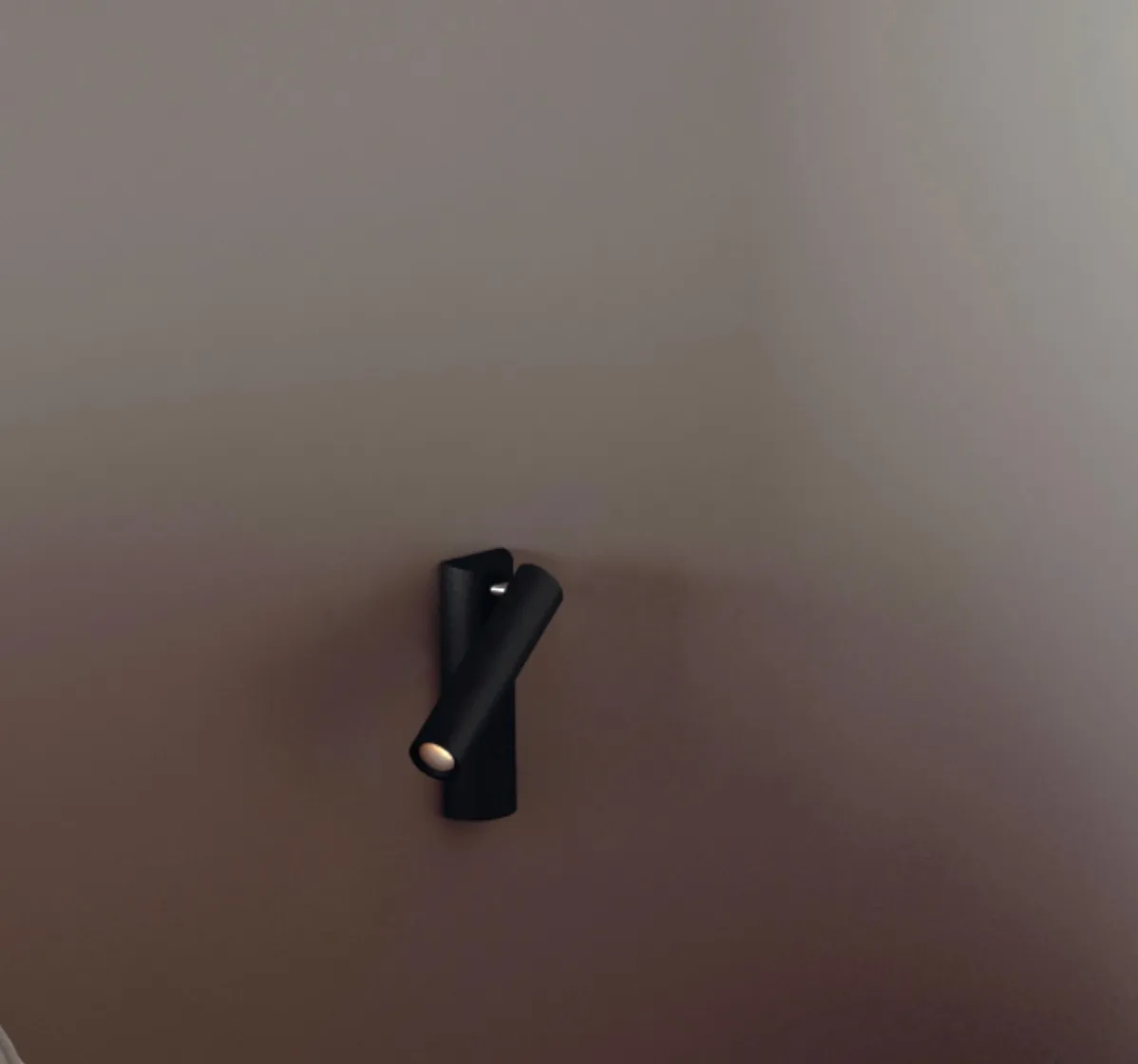 Schwarze ENSO Lese-Einbauleuchte in realer Anwendung an einer dunklen Wand mit warm leuchtendem, fokussiertem Leselicht
