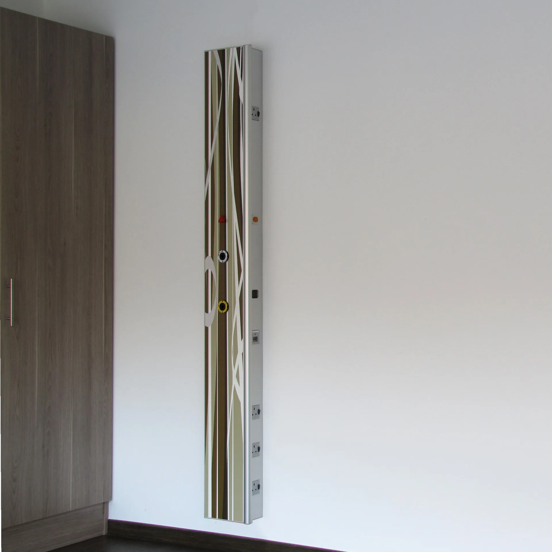 Vertical supply column pure with graphic stripe decor in shades of brown and green next to a wooden wall unit in a bright patient room