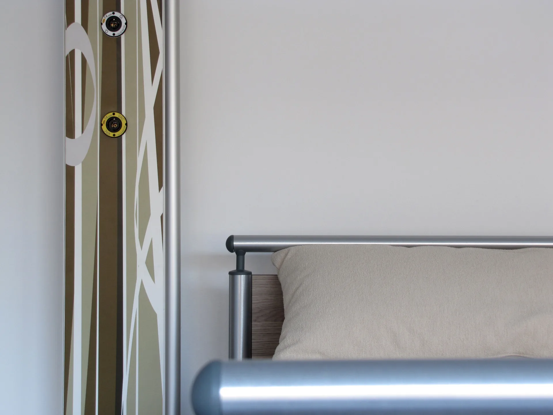 Close-up of a pure supply column with a graphic stripe decor and gas connections next to a care bed with a metal frame
