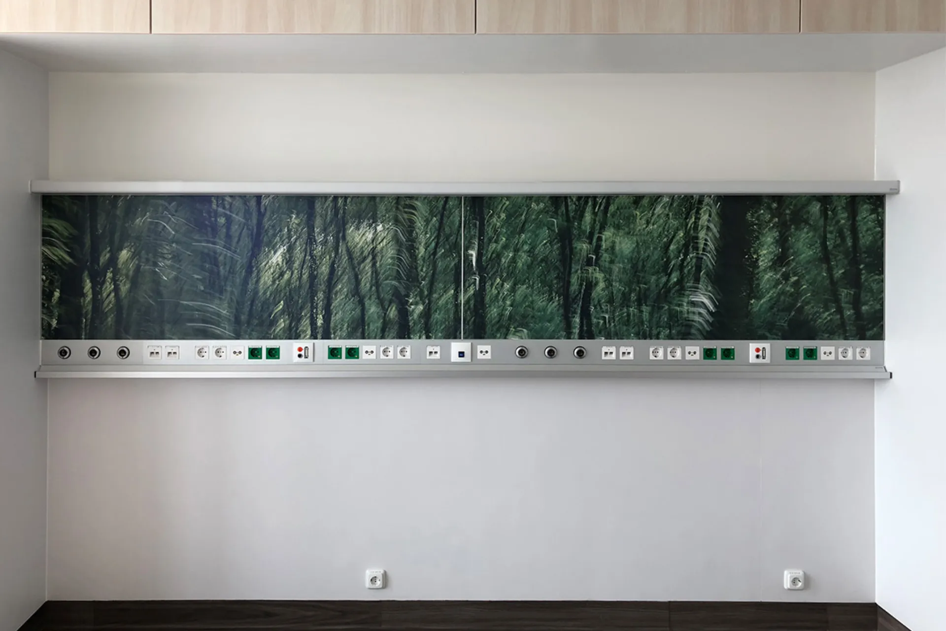 Wall-mounted supply unit with a socket strip and a digitally printed motif of a dark forest