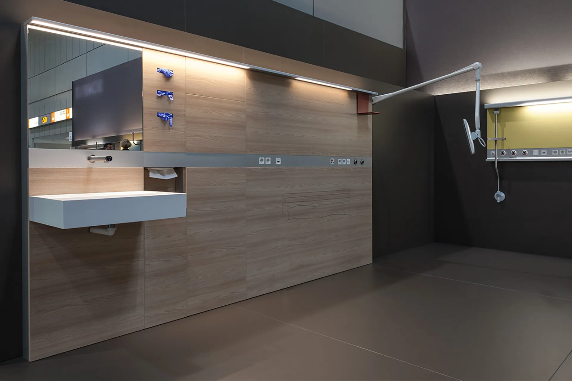 Modern, empty treatment room with wood panelling, a washbasin and medical connections on the wall