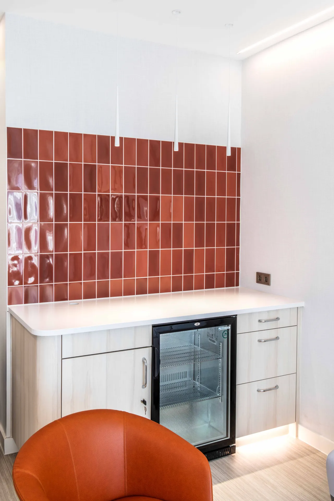 A red-tiled recess in a patient room with pendant luminaires above a worktop.
