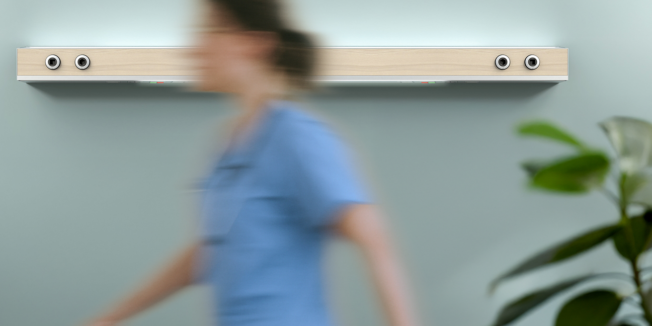 A nurse walks down a bright hospital corridor.